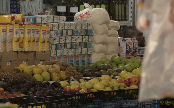 Variety of fresh fruits and products displayed in a grocery store aisle with clear copyspace.