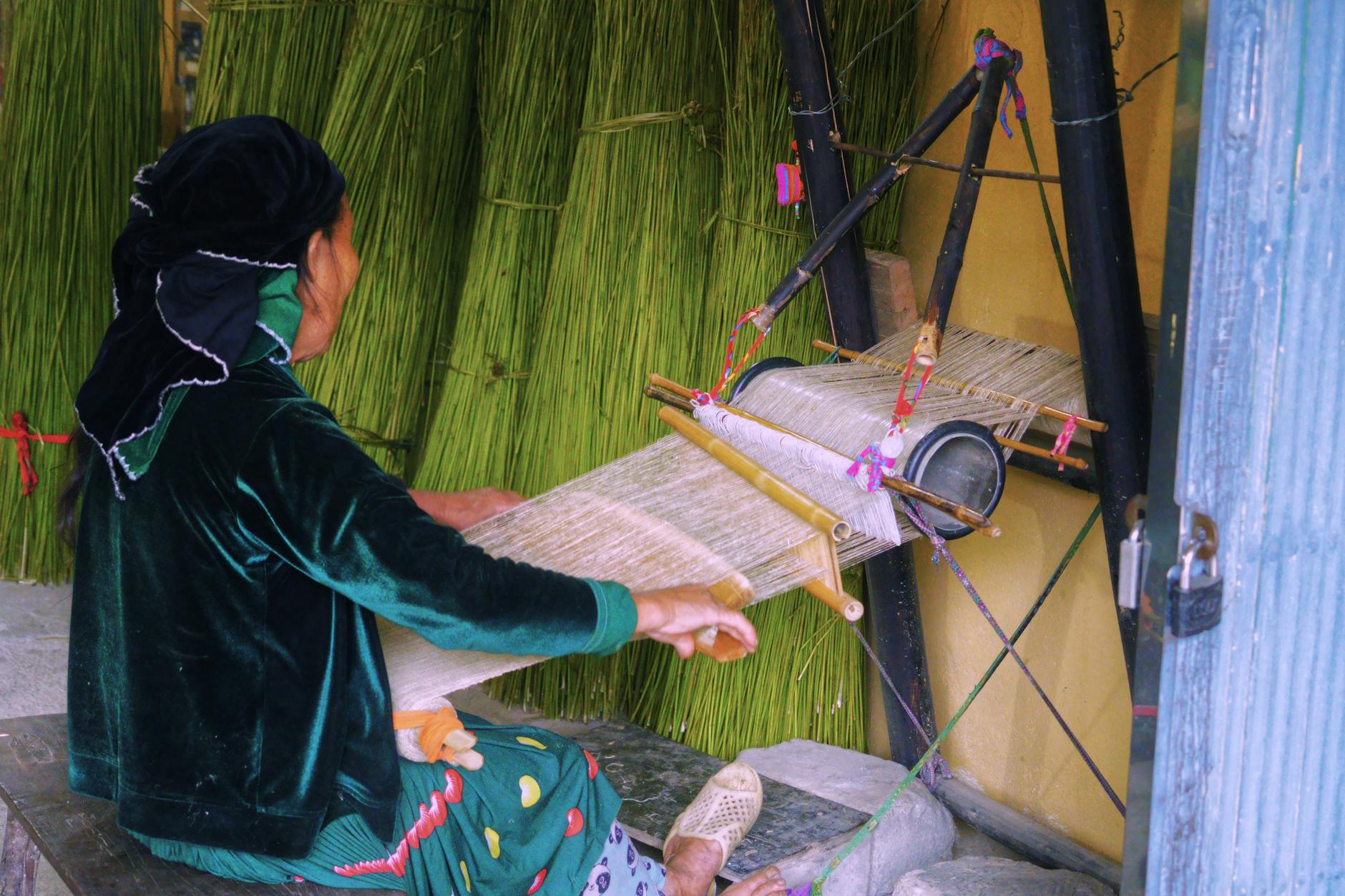 A woman skillfully weaving textiles on a traditional loom indoors, showcasing cultural craftsmanship.