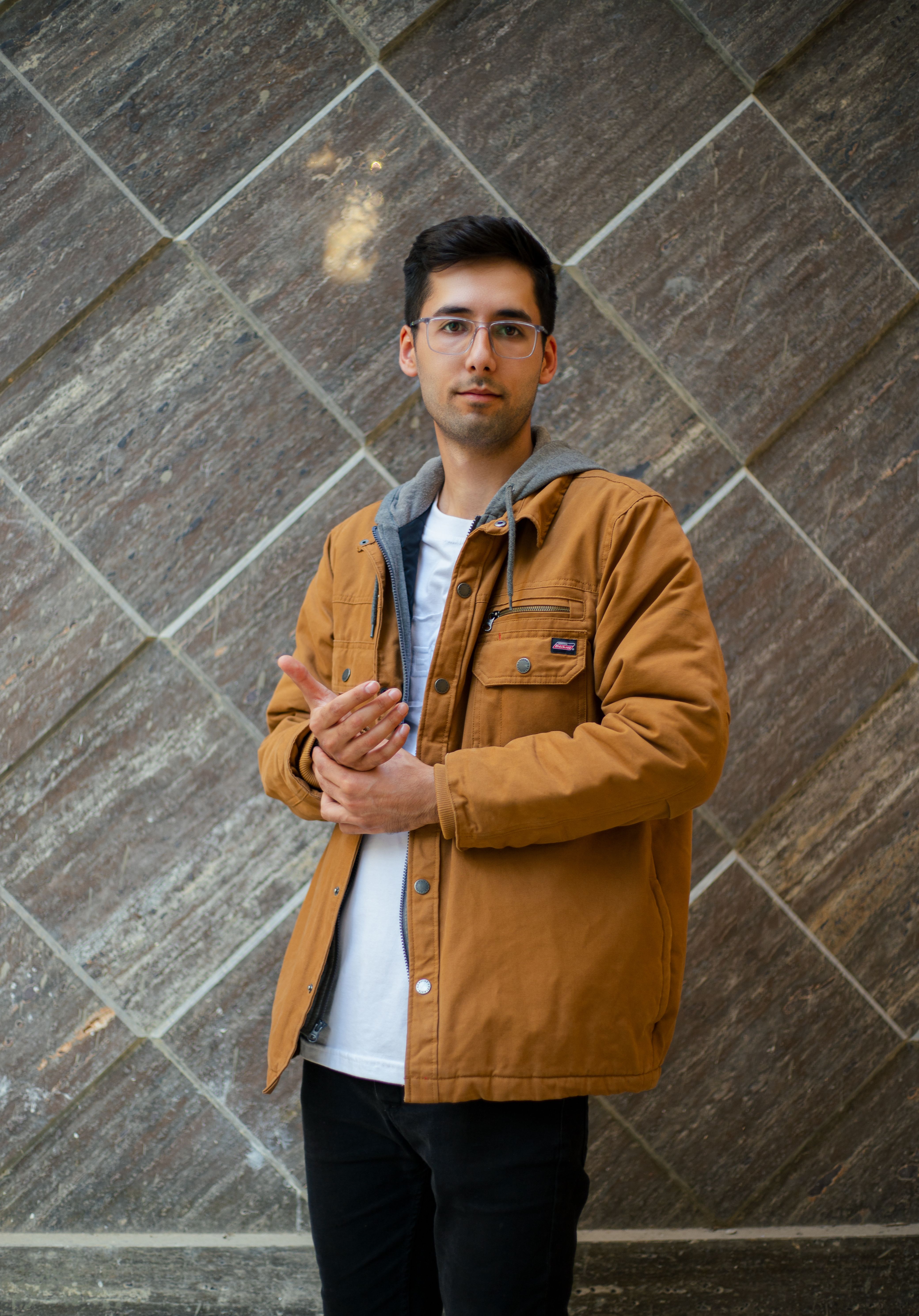 Young Man in a Orange Jacket Against the Wall · Free Stock Photo