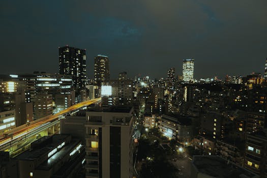Aerial view of a vibrant cityscape at night with illuminated skyscrapers and buildings, showcasing urban architecture.