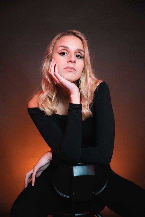 Free Model posing with orange backlight, showcasing modern fashion in a studio setting. Stock Photo