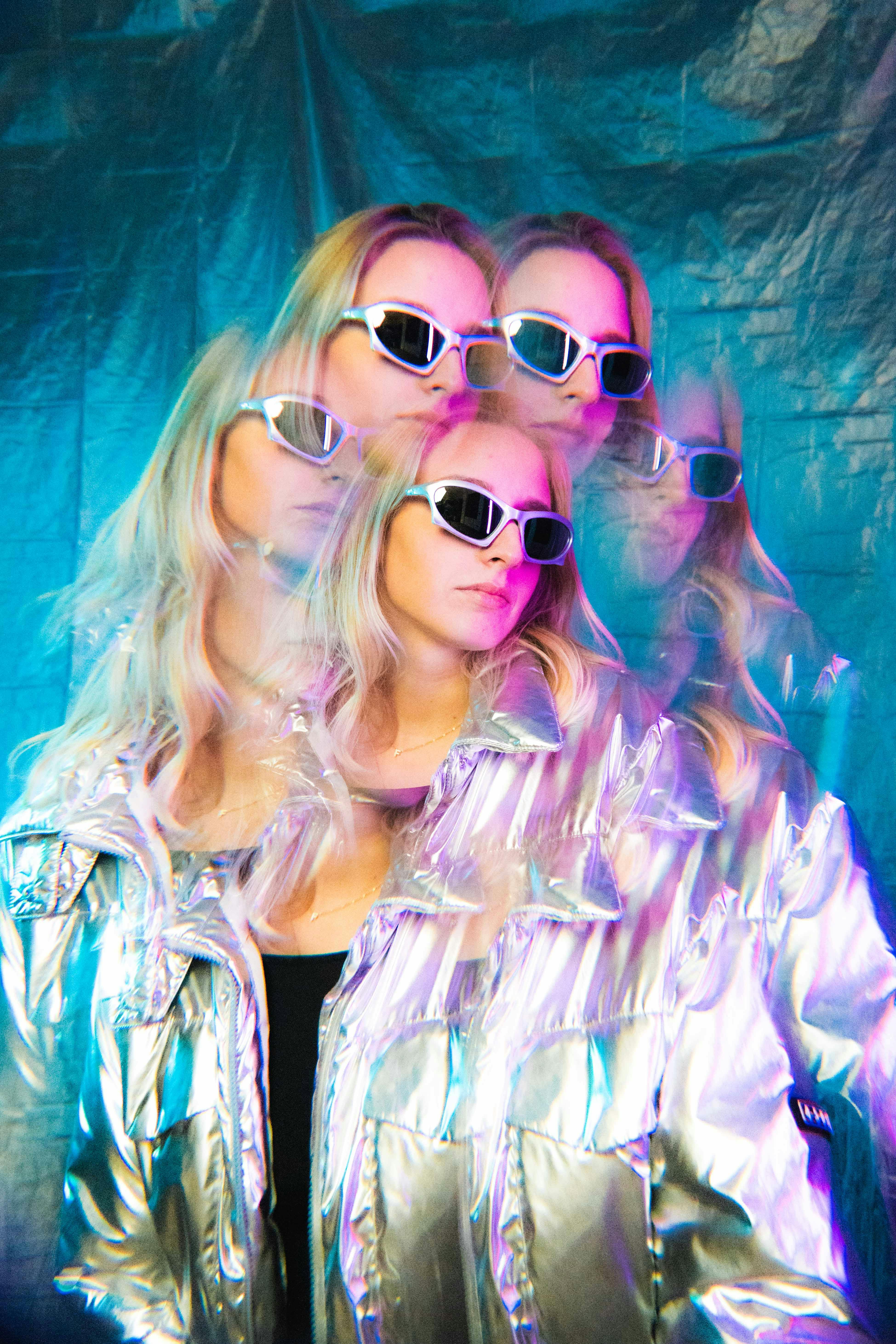 Artistic portrait of a woman in a silver jacket with multi-exposure effect wearing sunglasses.