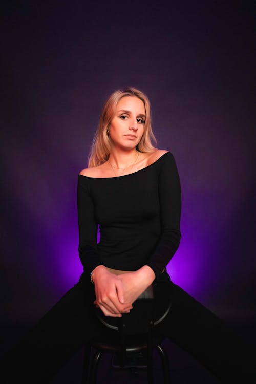 Model in a Black Blouse Posing in a Studio with Purple Backlight