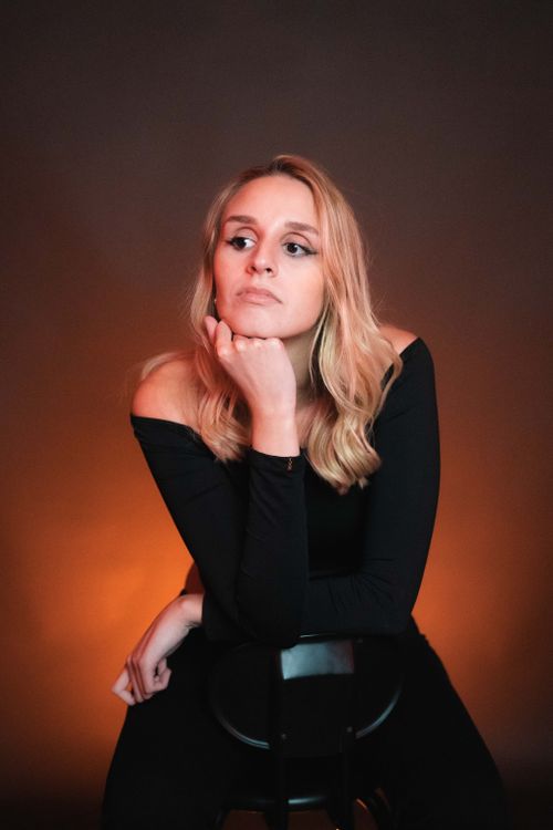 Free Thoughtful blonde woman posing in a moody studio setting. Perfect for editorial use. Stock Photo
