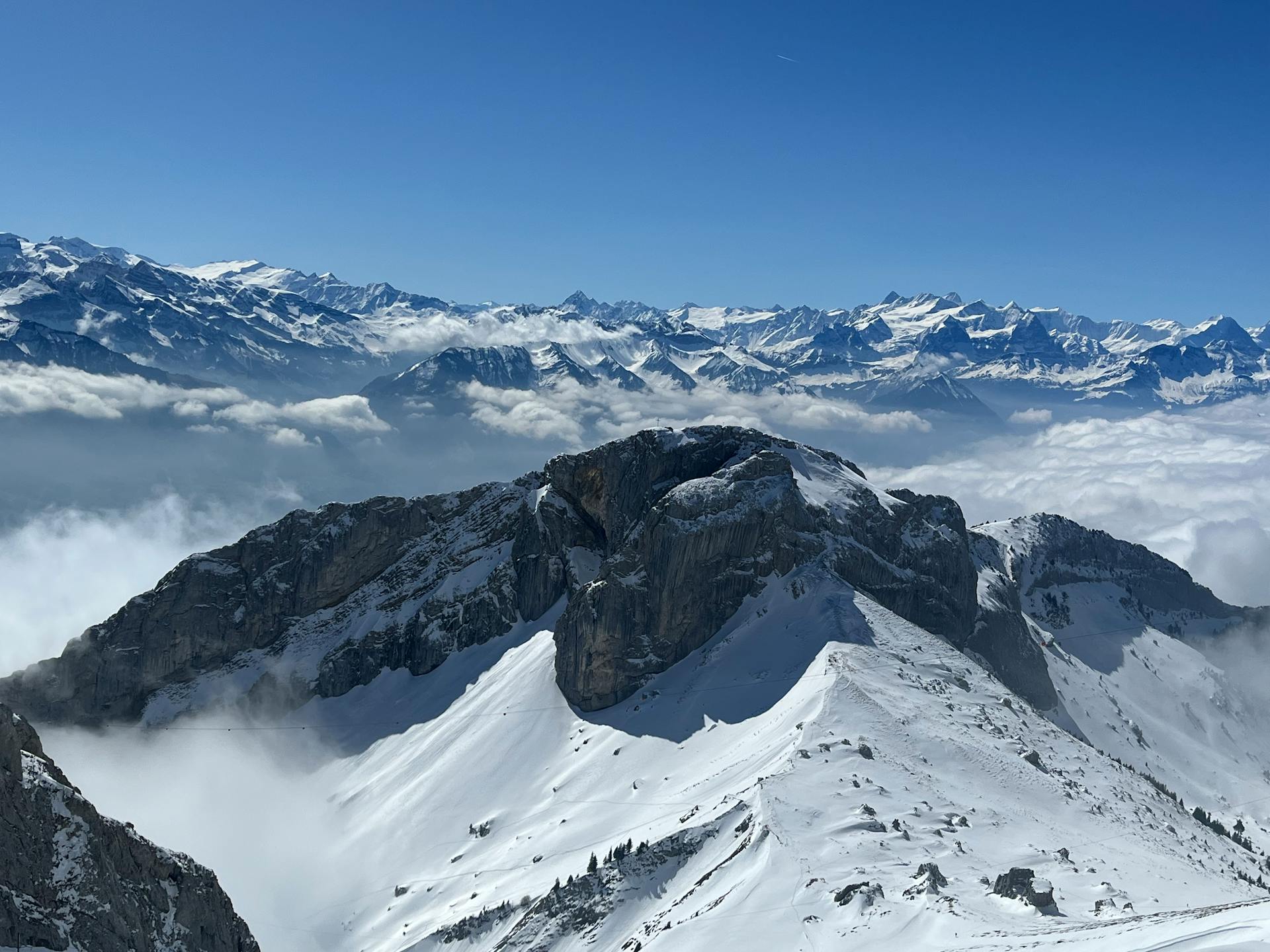 Breathtaking view of snow-capped Swiss Alps under a clear blue sky in Alpnach, Switzerland.