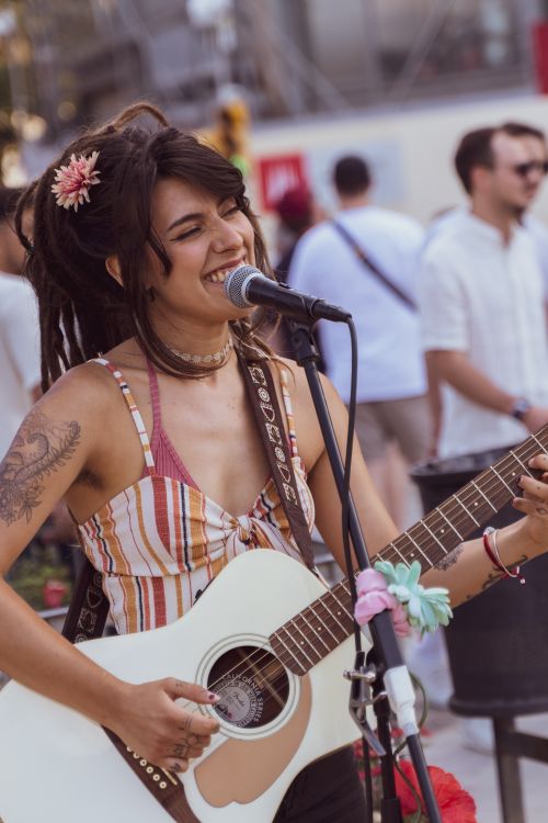 Free A vibrant female street performer sings and plays guitar in a lively Barcelona setting. Stock Photo