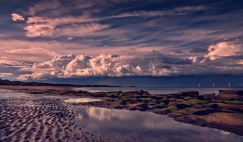 Free A serene seaside landscape with dramatic clouds and gentle waves at dusk. Stock Photo