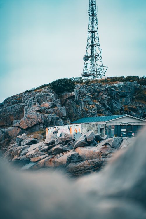 Free A rustic scene in Henningsvær, Norway, showcasing rocky terrain with a tower and ocean view. Stock Photo