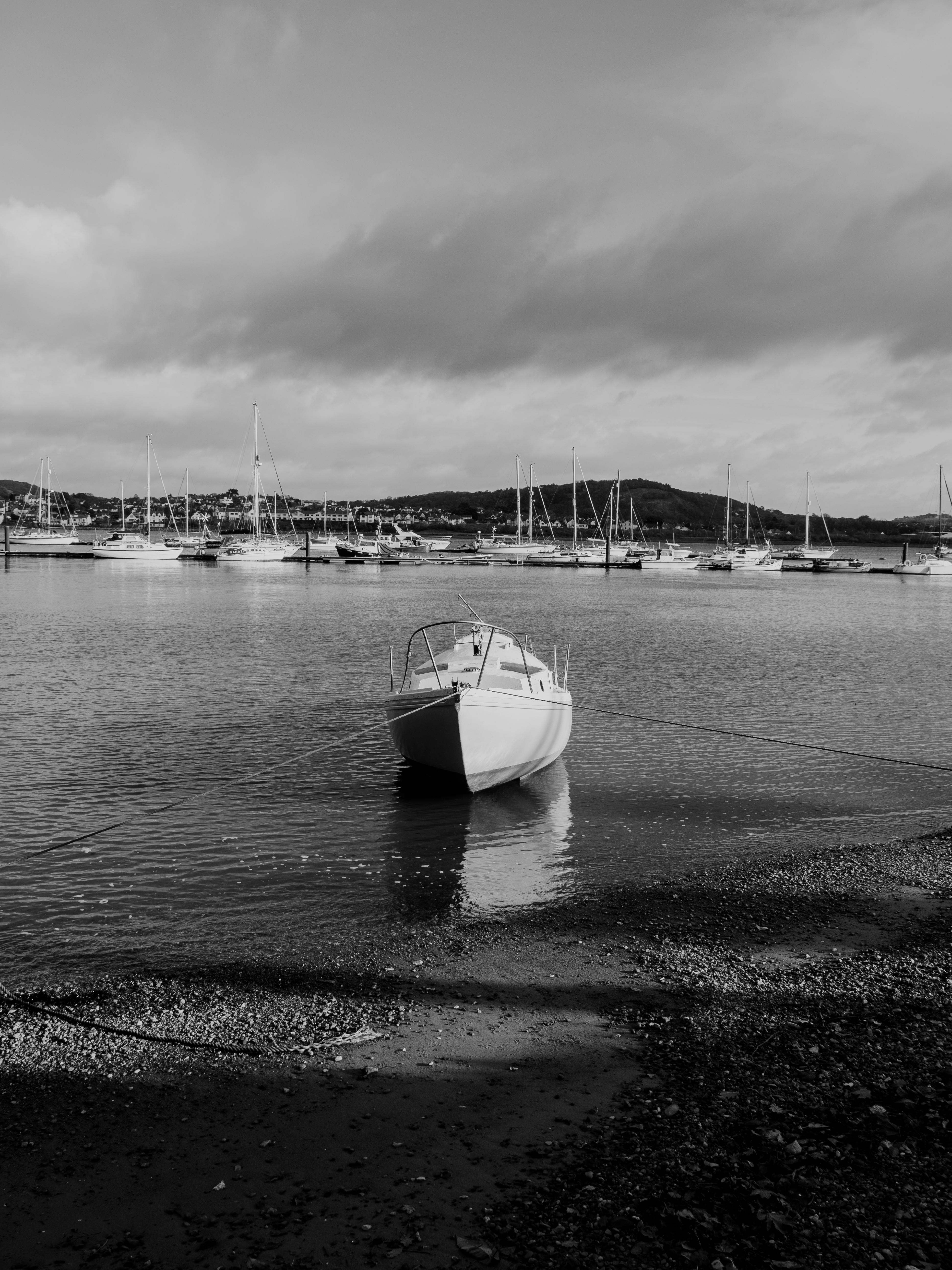A tranquil black and white image of moored boats in Conwy Harbor, Wales, with a focus on a single motorboat.