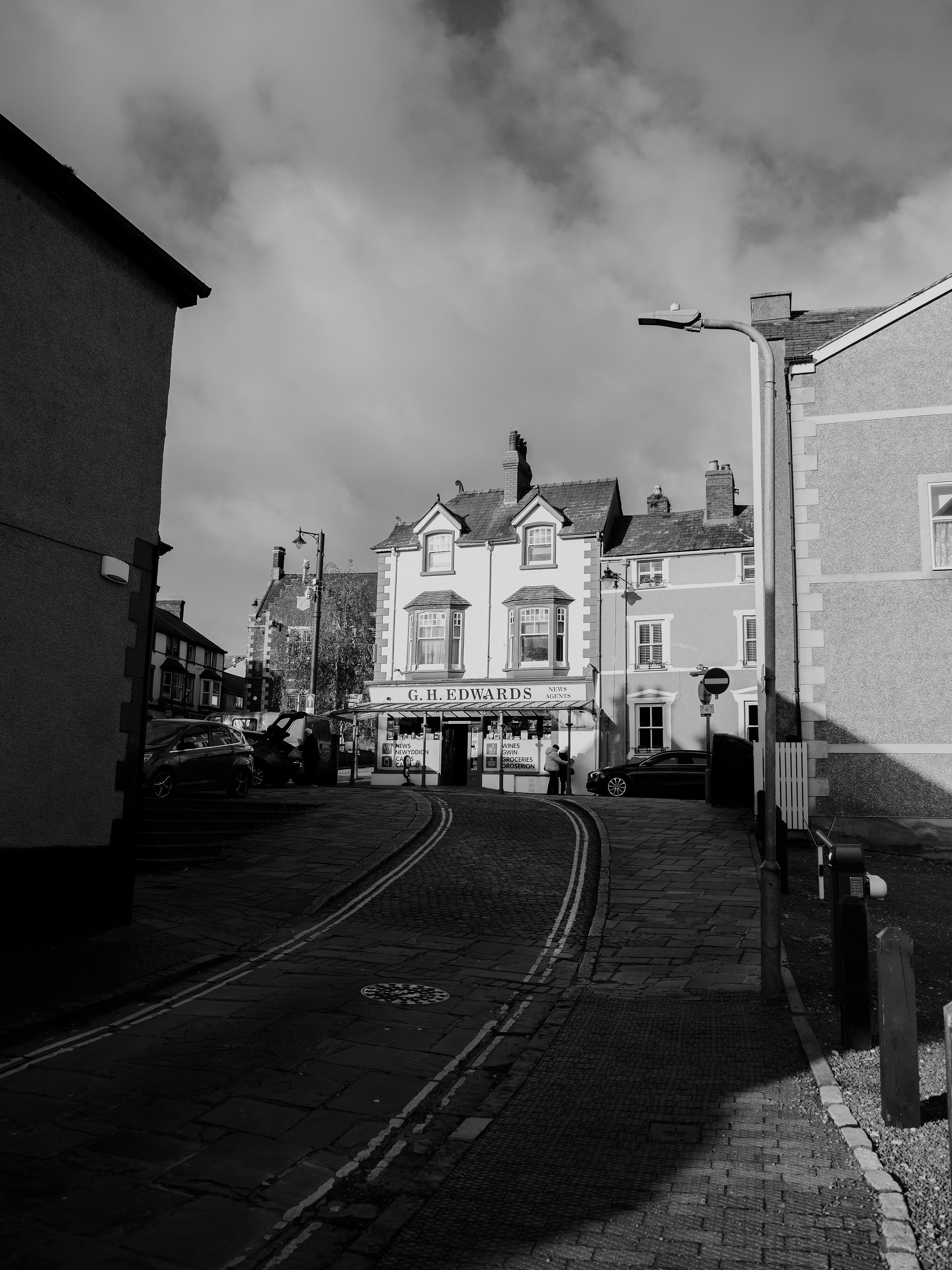 Charming black and white street scene in Conwy, Wales with historic architecture and paving stones.