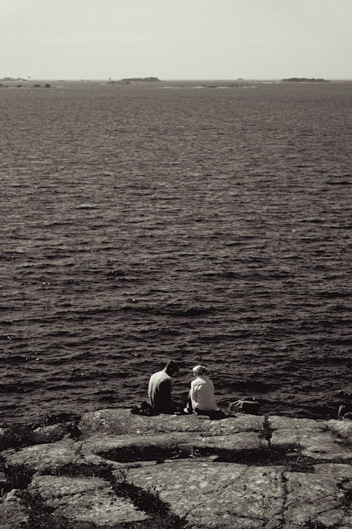 Couple Sitting Together on the Rock by the Sea 