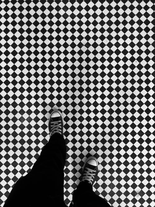 Free Black and white photo of Converse shoes on a geometric tiled floor, top view. Stock Photo