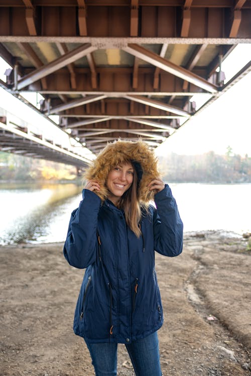 Smiling Woman in Jacket Posing under Bridge