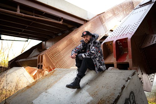 Young Man in a Baseball Cap Sitting under a Bridge 