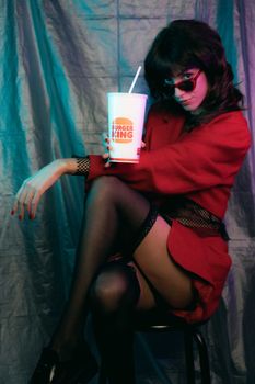 Portrait of a stylish woman in red attire posing with a branded beverage cup.