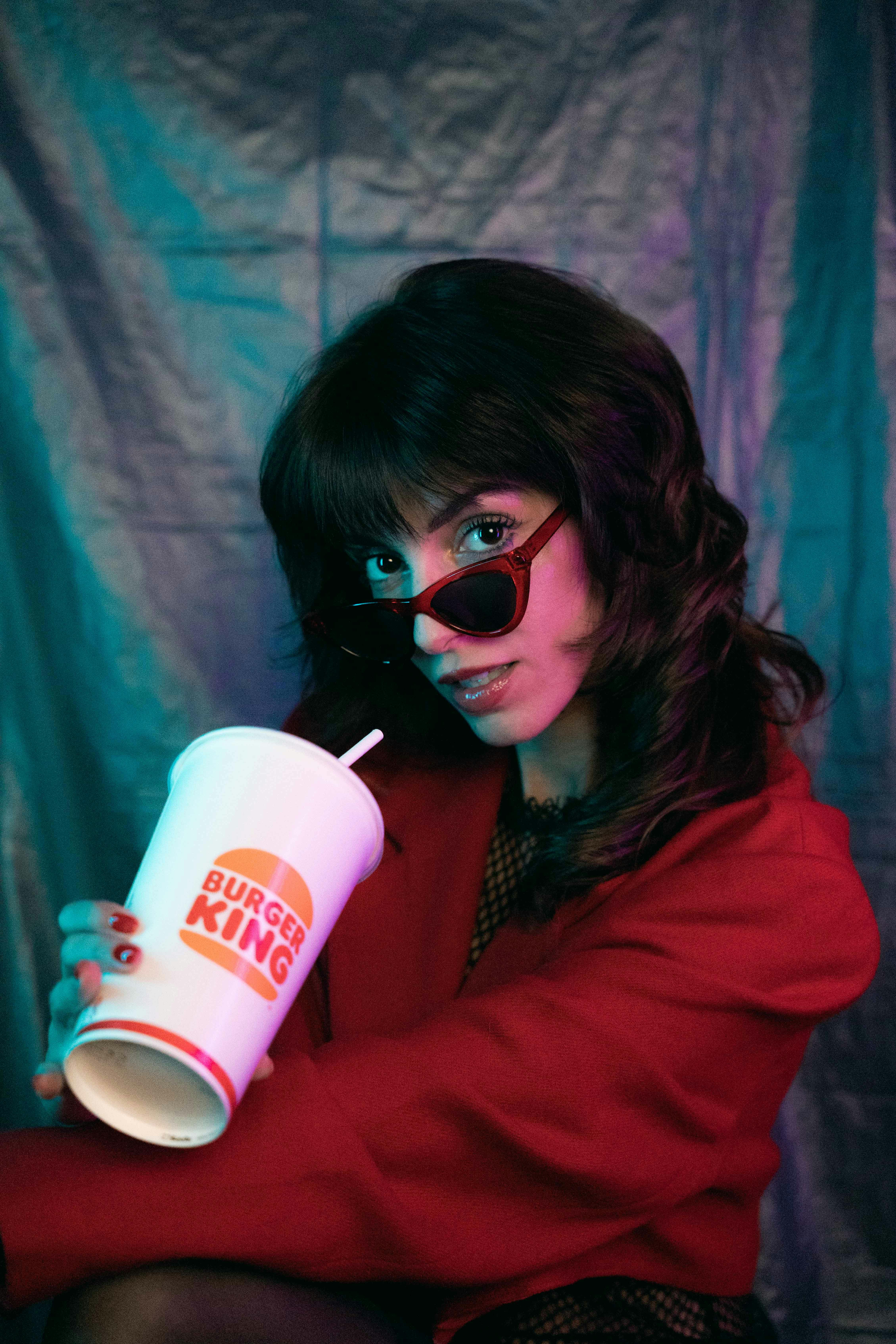 brunette in sunglasses posing with beverage