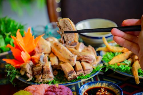 Free Close-up of chopsticks lifting a piece of cooked meat from a vibrant dish with dipping sauce. Stock Photo