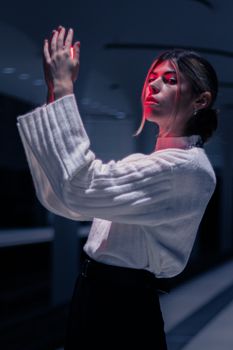 Fashionable woman posing indoors with dramatic red lighting.