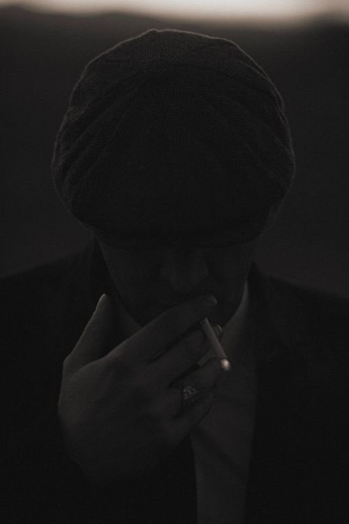 Free A mysterious figure in a hat smoking, set against a dark, moody backdrop. Stock Photo