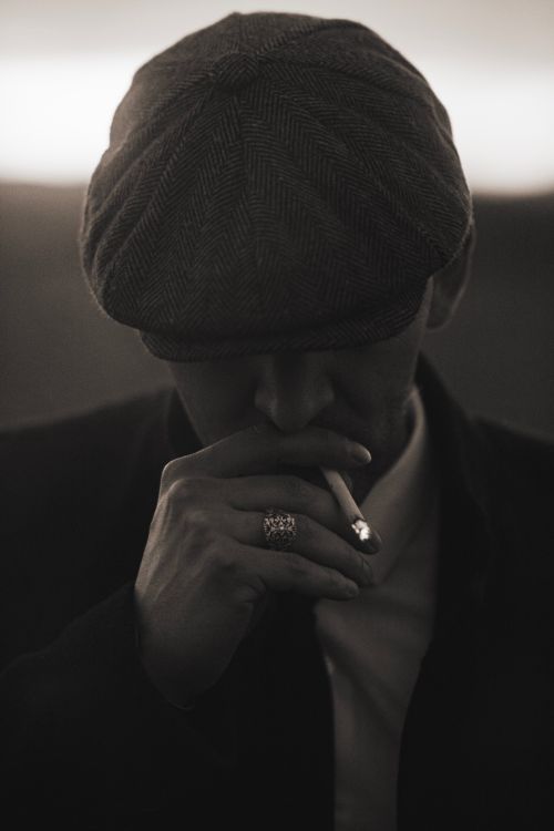 Free Mysterious black and white portrait of a man in a hat smoking, exuding elegance and introspection. Stock Photo