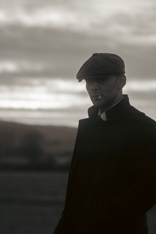 Free Stylish black and white portrait of a man standing outdoors, smoking. Stock Photo
