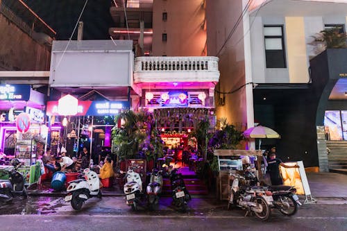 Vehicles Parked in front of an Illuminated Bar in City 