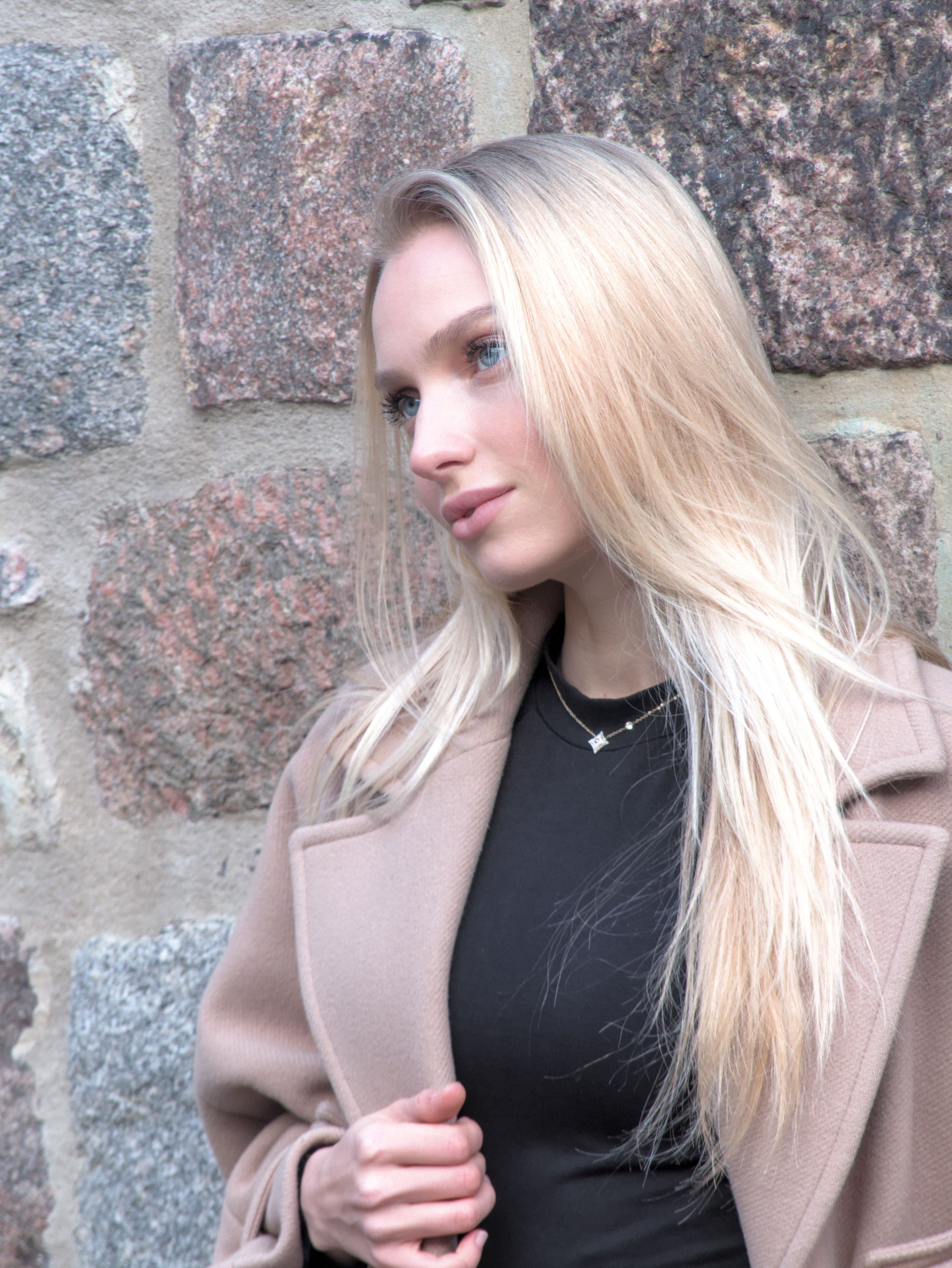 Young woman posing elegantly against a stone wall in Berlin.
