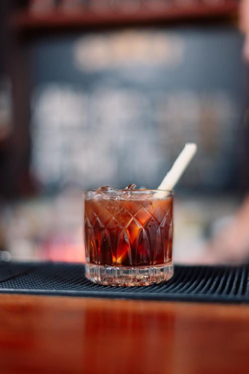 Free A refreshing iced cocktail served in a crystal glass with a straw on a bar counter. Stock Photo