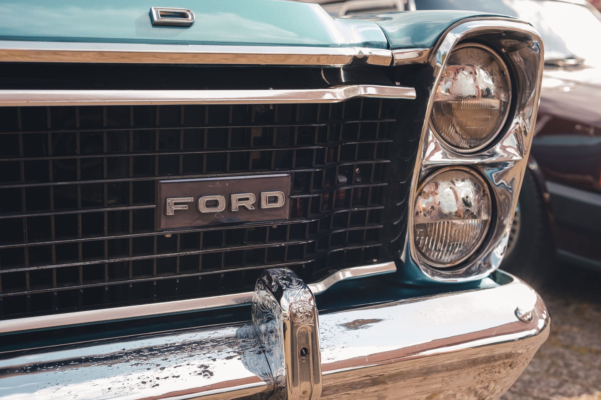 Close-up view of a vintage Ford car's grille and headlight, emphasizing its classic design.