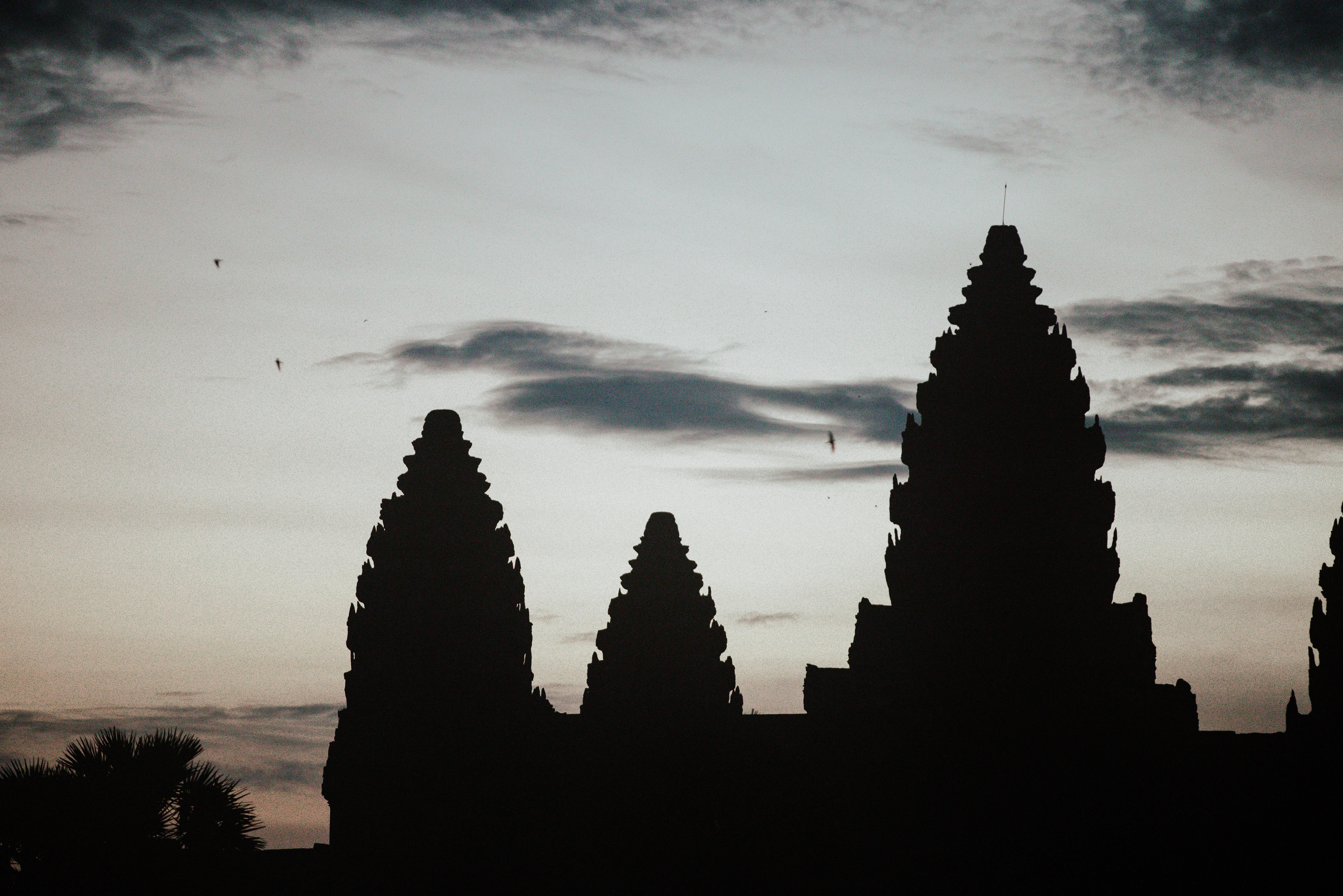 Dramatic silhouette of Angkor Wat temples against a twilight sky.