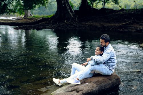Free Happy couple sitting by the river, embracing nature's serenity in a rural setting. Stock Photo
