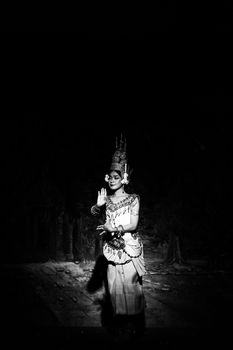 Captivating black and white image of a woman performing a traditional dance on stage.