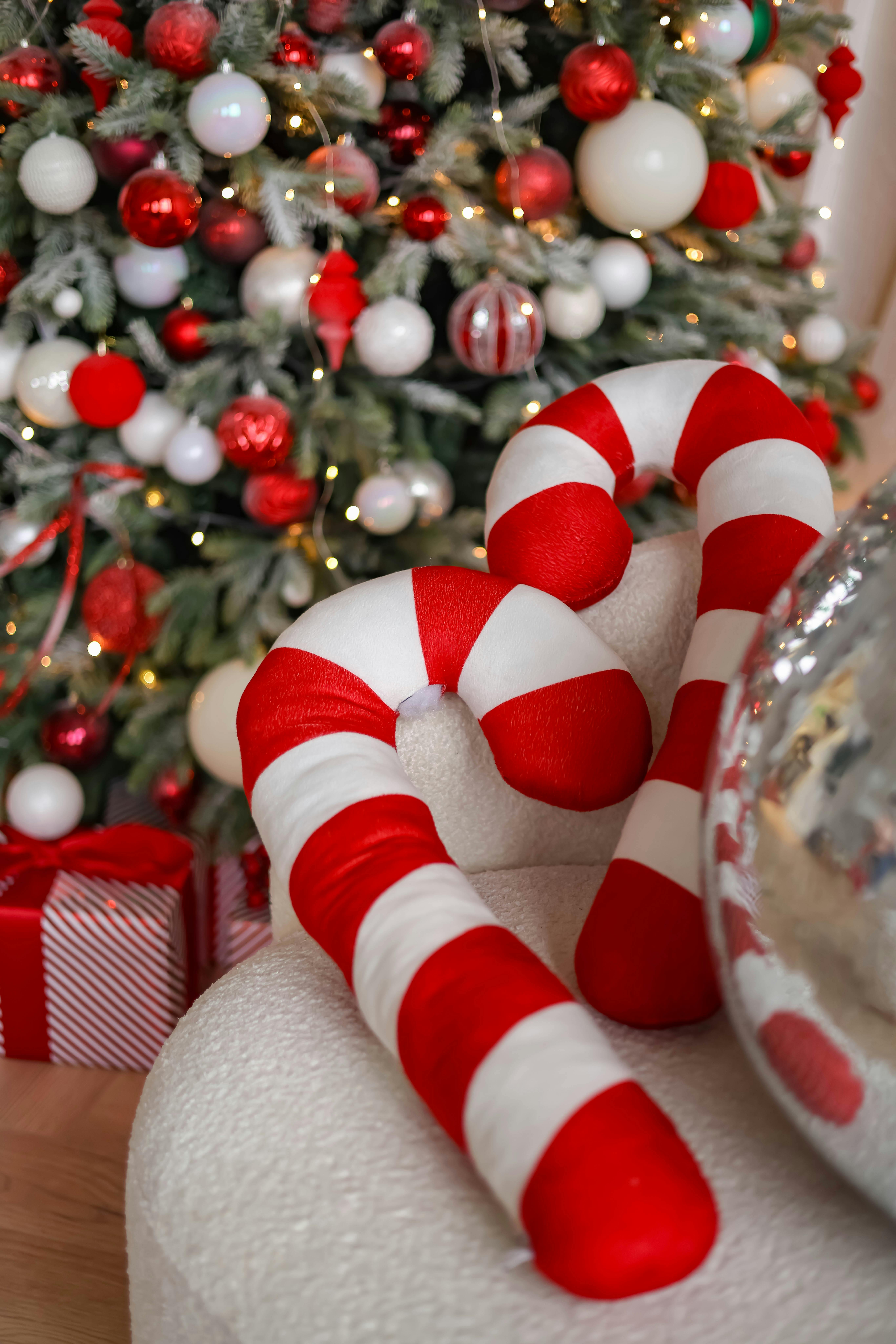 Close-up of a decorated Christmas tree with candy cane ornaments and gifts, capturing holiday spirit.