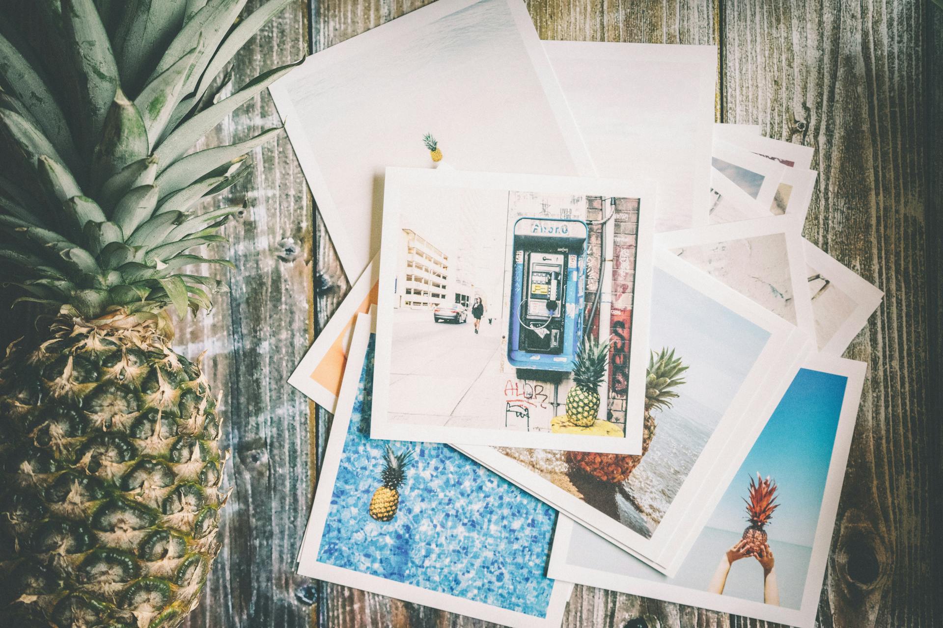 Assorted Photo Beside Pineapple on Top of Brown Surface