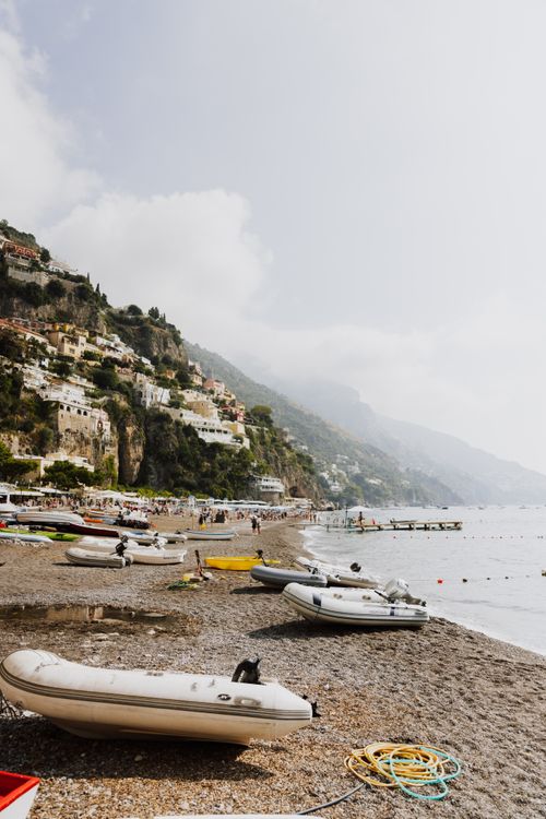 Free A breathtaking view of Positano's beach with inflatable boats, cliffs, and vibrant architecture. Stock Photo