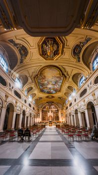Capture of an ornate church interior featuring a detailed painted ceiling and lined-up chairs in a vertical shot.