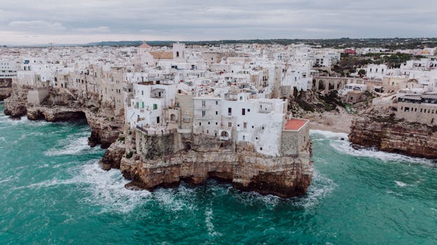 Explore the stunning cliffside architecture of Polignano a Mare in southern Italy overlooking the turquoise sea.