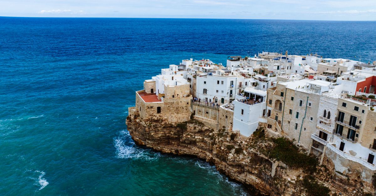 aerial view of coastal town with few tourists, dramatic cliffs