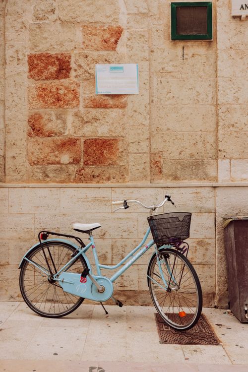Free A retro bicycle is parked against a rustic, textured wall in an urban setting, evoking nostalgia. Stock Photo