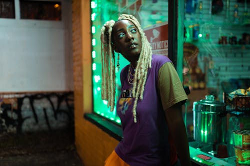 밤에 가게 밖에 서 있는 금발 머리를 가진 흑인 소녀