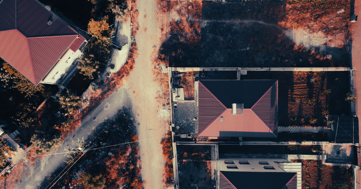 Aerial view showcasing suburban houses with red roofs and adjacent streets.