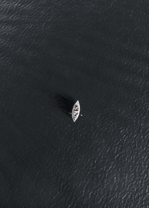Free Aerial shot of a lone kayak paddling across the vast ocean water. Stock Photo