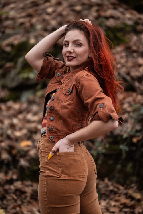 Red Haired Model in Brown Jeans and a Denim Jacket in the Forest
