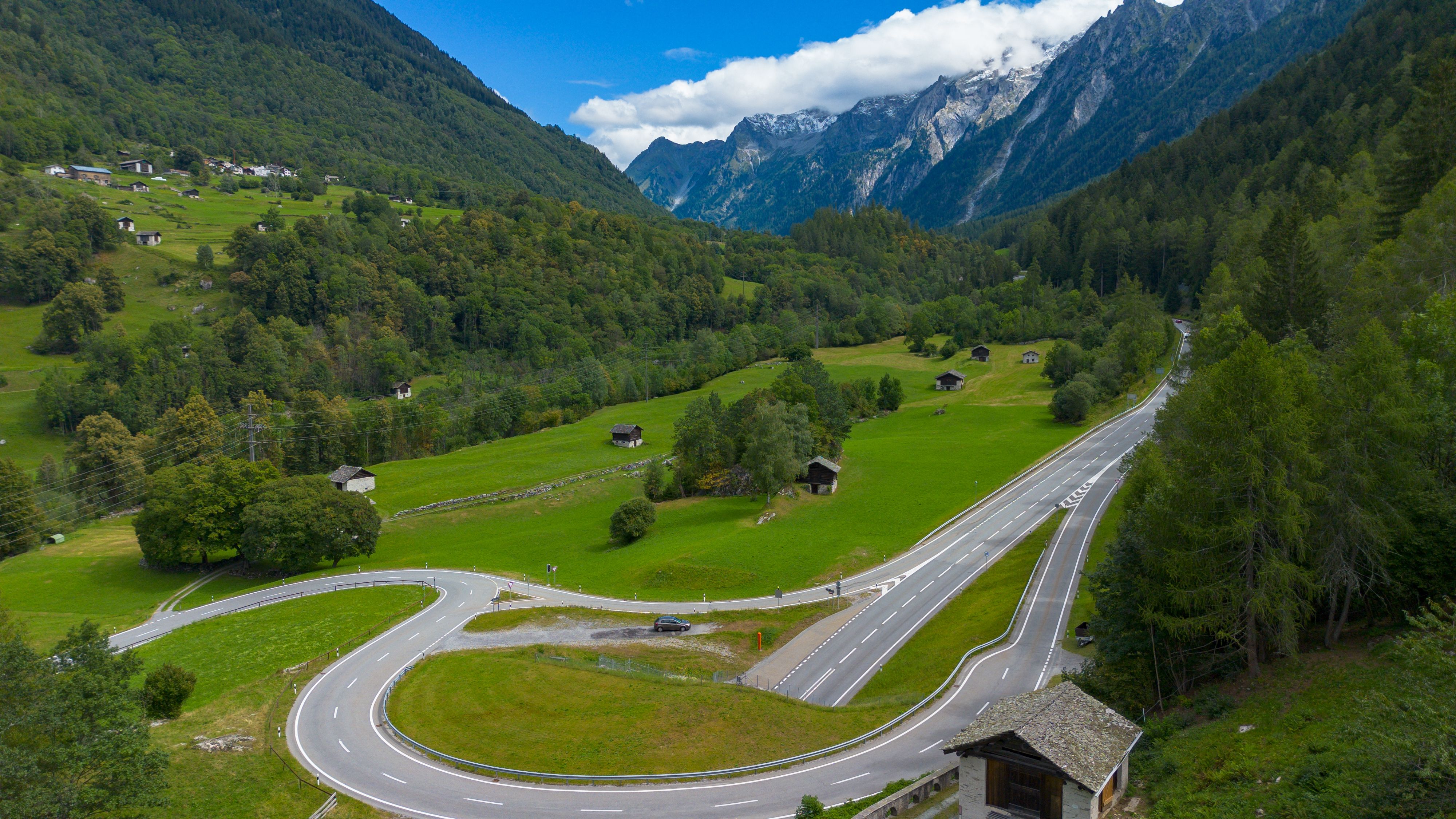 Breathtaking Private Swiss Alps Helicopter Tour Over Snow Covered Mountain Peaks and Glaciers Review Review 2026 - A winding road cuts through the lush green valley of Bregaglia, Switzerland with mountain views.