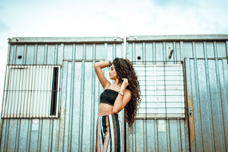Chic young woman in fashionable attire posing confidently against a metal container backdrop.