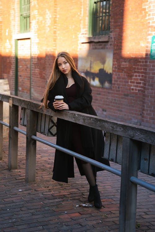 Model in Coat Posing with Disposable Cup