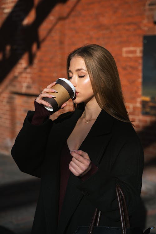 Woman in Coat Drinking Coffee from Disposable Cup