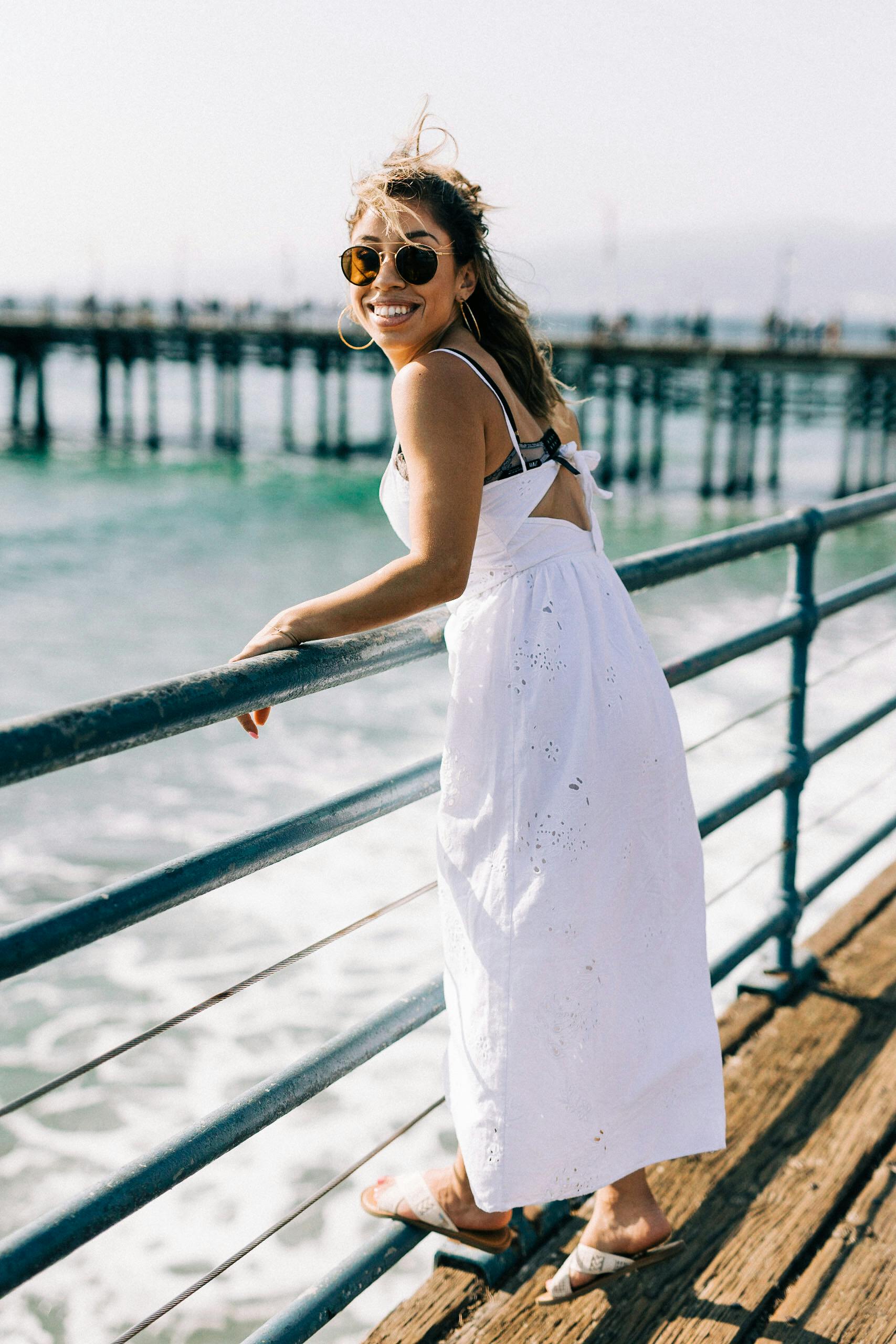 Smiling woman in white dress enjoying summer at Santa Monica Pier.