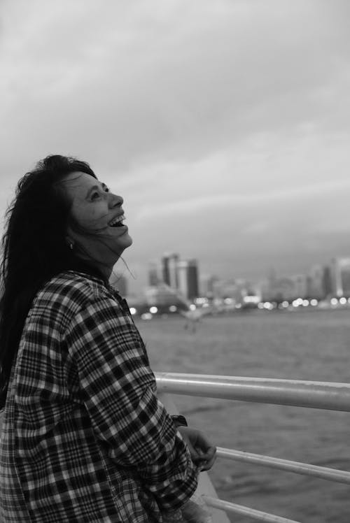 Smiling Woman in Shirt Standing by Railing on Sea Shore in City