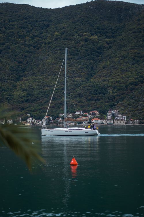 Free A serene yacht sails on a tranquil mountain lake, surrounded by lush hills. Stock Photo